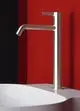 Moderner Wasserhahn von Ideal Standard in Silber, montiert über einem weißen Waschbecken vor einer rot-schwarzen Wand. Der Auslauf hat eine gerade Form.